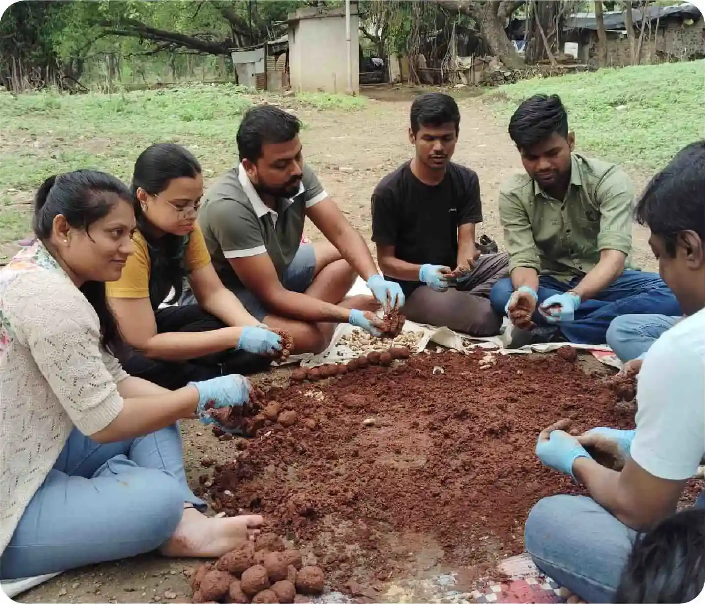 Volunteers preparing seed balls by mixing soil and seeds during plantation activity